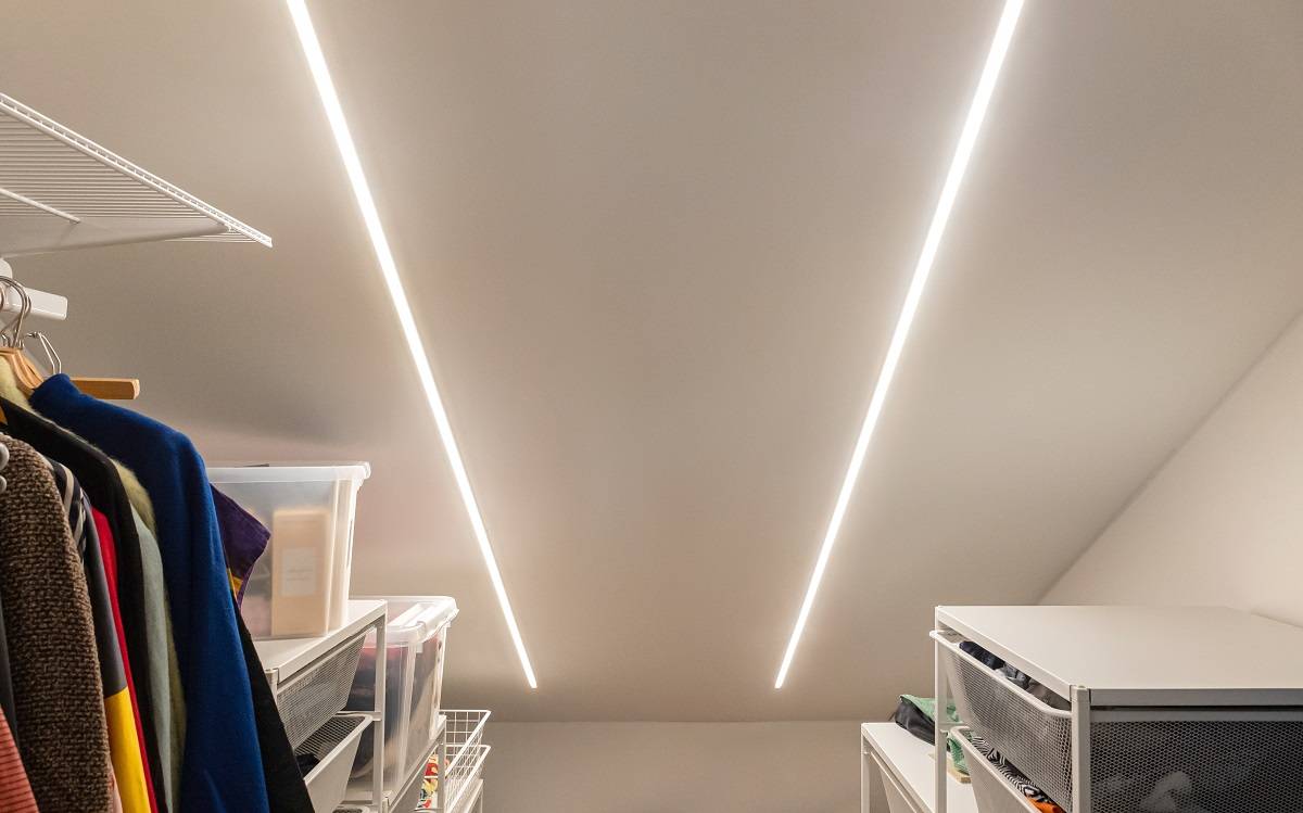 Dva LED pásky zapuštěné do strmého stropu šatní skříně.